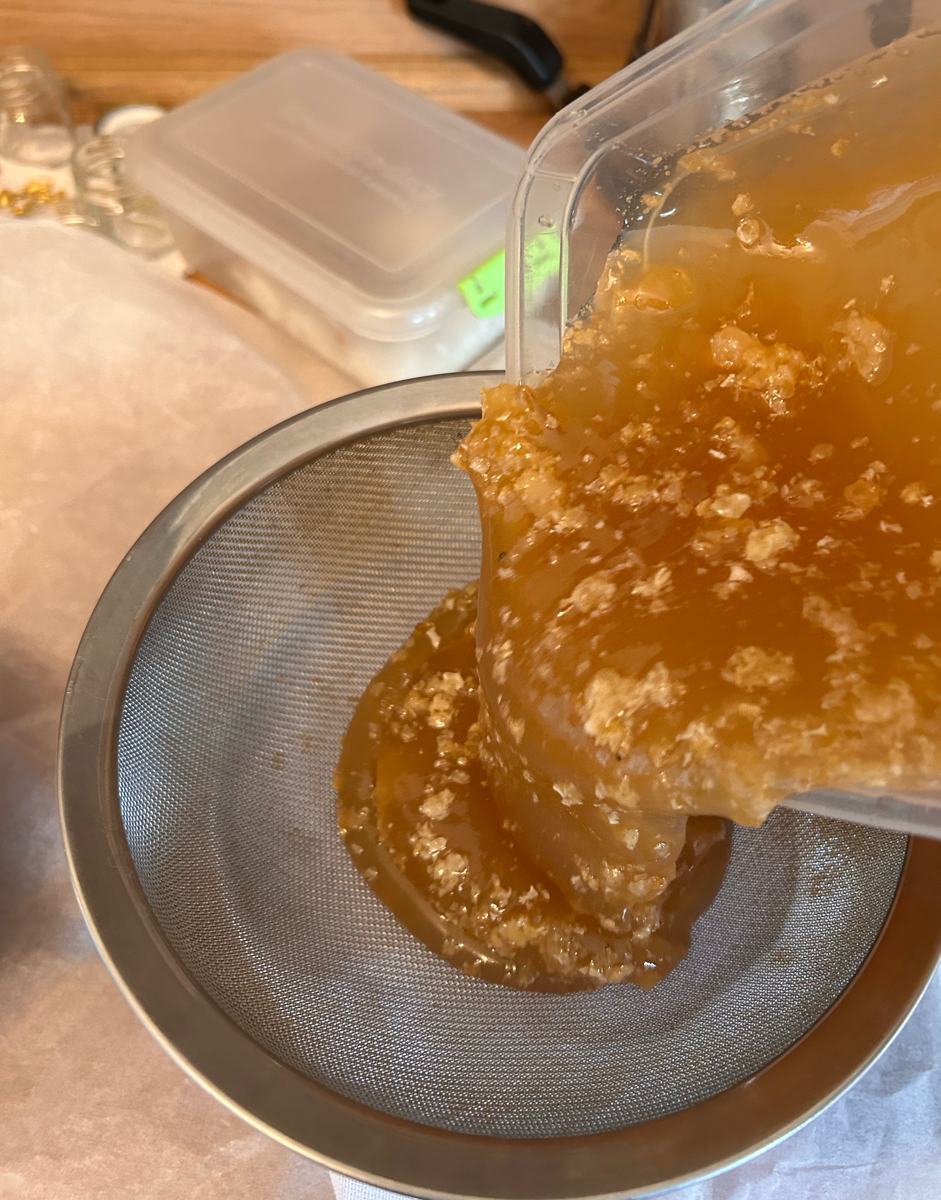 Honey and wax poured from the extractor into a steel sieve