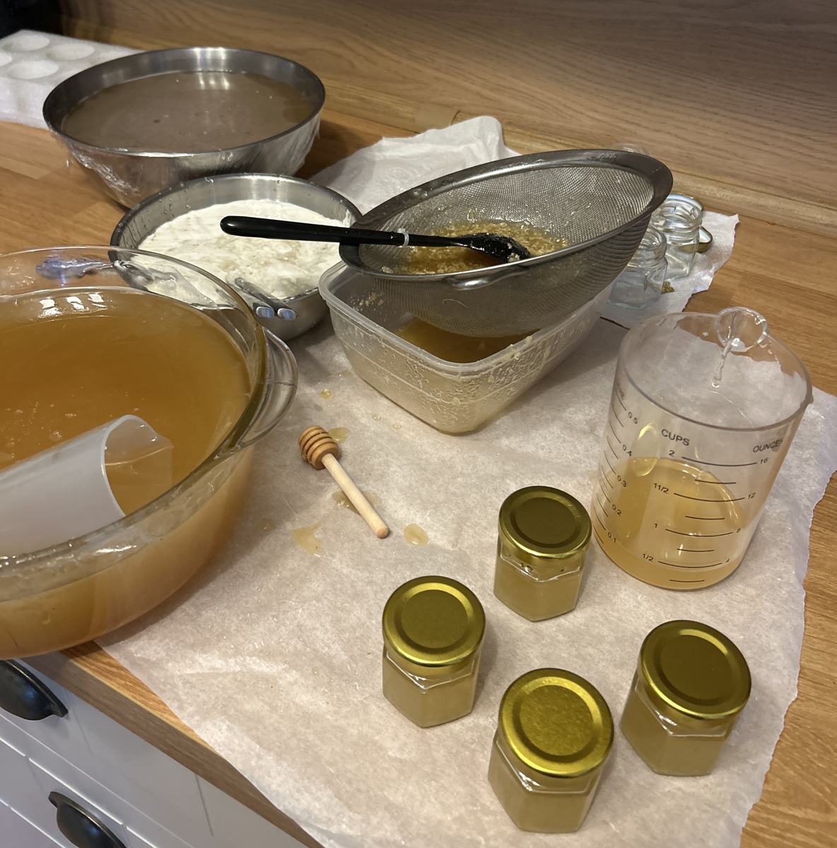 The jarring station: strained honey, sieve and freshly filled jars on clean baking paper